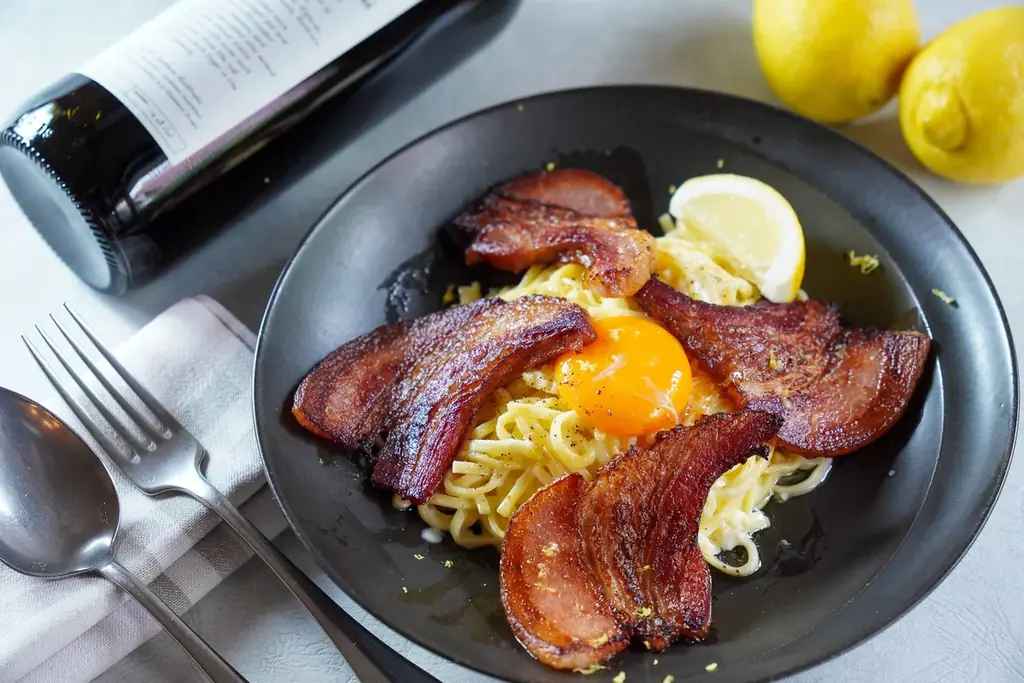 濃厚ベーコンとレモンの香りが引き立つ、新感覚カルボナーラ！燃えるチーズの中で仕上げる【炎のチーズパスタ】新商品「厚切りイベリコ豚ベーコンのレモンカルボナーラ」を販売開始します。 画像 1